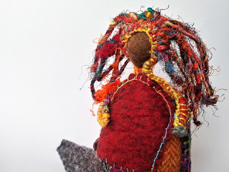 A handmade doll with multi-coloured hair