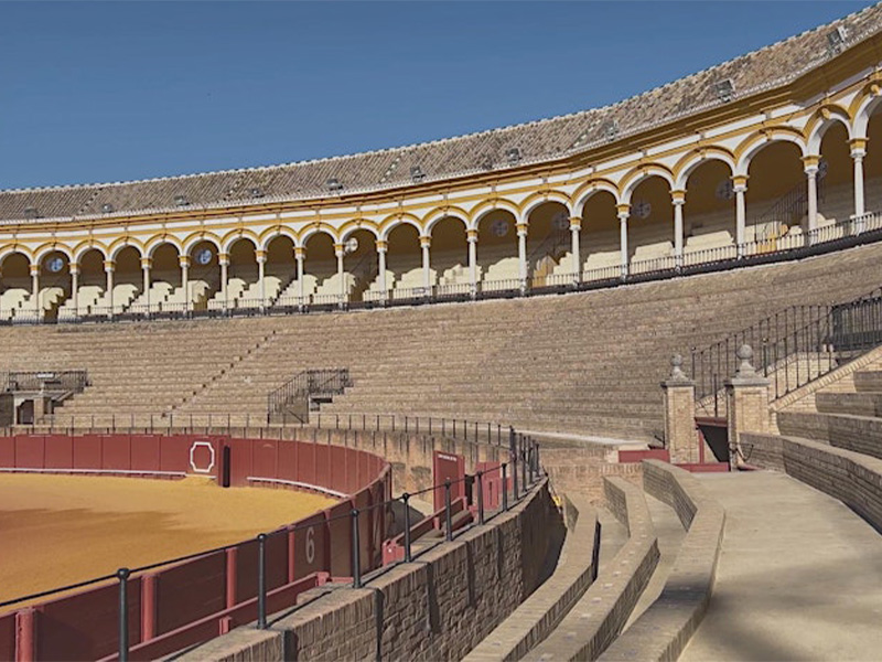 An open-air stone theatre with rounded arches up top and red fencing around the arena space